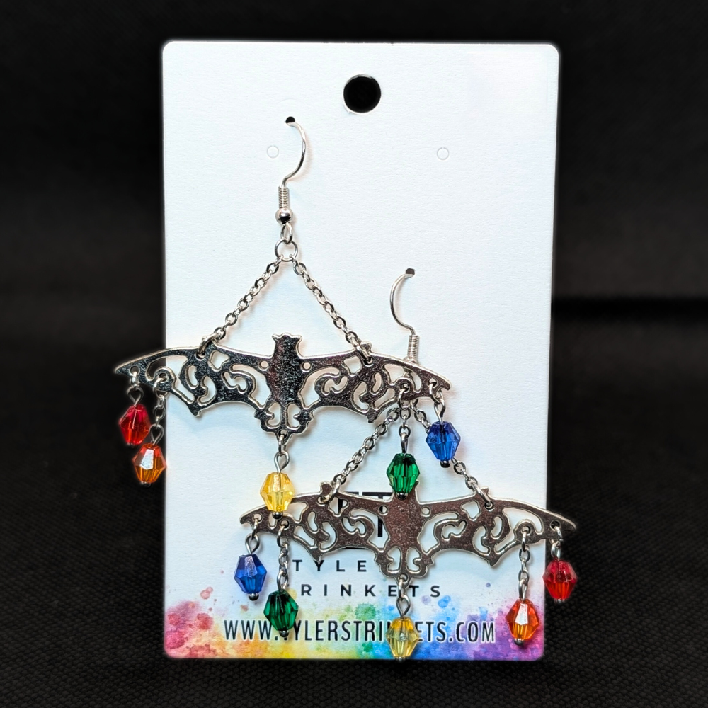 Dangle earrings made from a metal bat-shaped charm and multi-colored beads on an ear-wire style hook.