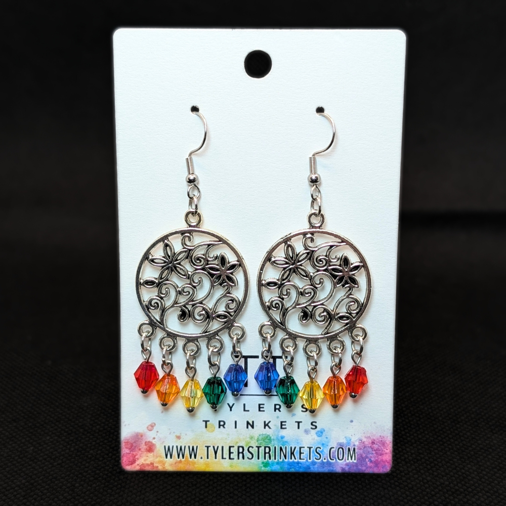 Dangle earrings made from a circular metal charm with a flower pattern in the center and multi-colored beads on an ear-wire style hook.